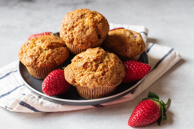 Photo strawberry muffins served in a plate on a marble background close up