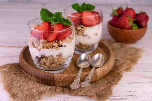 Strawberry parfait in a glass with yogurt and granola on a gray background