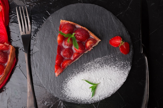 Strawberry pie on black slate plate. One piece. Top view.