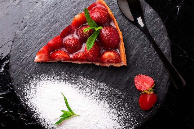 Strawberry pie on black slate plate.