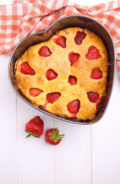 Torta di fragole a forma di cuore su sfondo bianco vista dall'alto