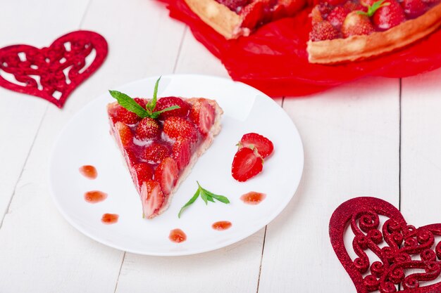 Strawberry pie on white plate and white wooden table