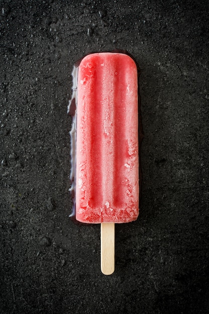 Strawberry popsicle on black stone top view