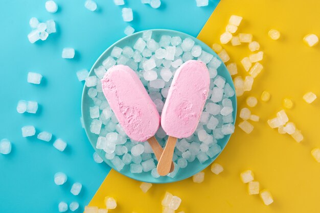 Strawberry popsicles and crushed ice on blue plate