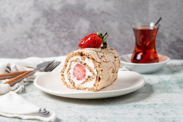 Strawberry Roll Cake Cream and strawberry log cake with tea on stone background close up