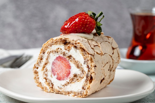 Strawberry Roll Cake Cream and strawberry log cake with tea on stone background close up