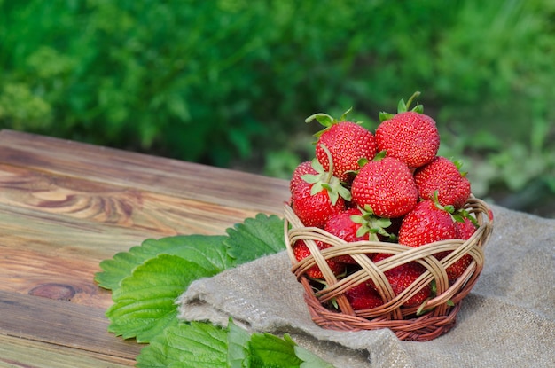 Strawberry on rustic wooden background Small basket full of strawberries Space for text