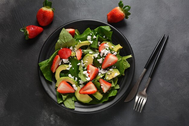 Insalata di fragole con spinaci, formaggio feta, avocado, aceto balsamico e olio d'oliva in un piatto