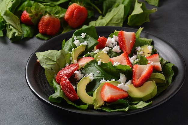 Strawberry Salad with spinach, feta cheese, avocado, balsamic vinegar and olive oil in a plate