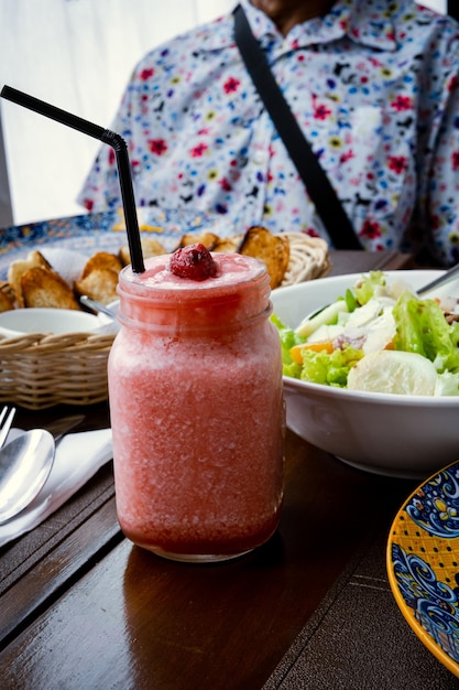 Foto strawberry shake, insalata di verdure e pane sul tavolo.