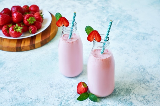 Frullato di fragole o frullato in barattolo di vetro con frutti di bosco su sfondo di cemento blu