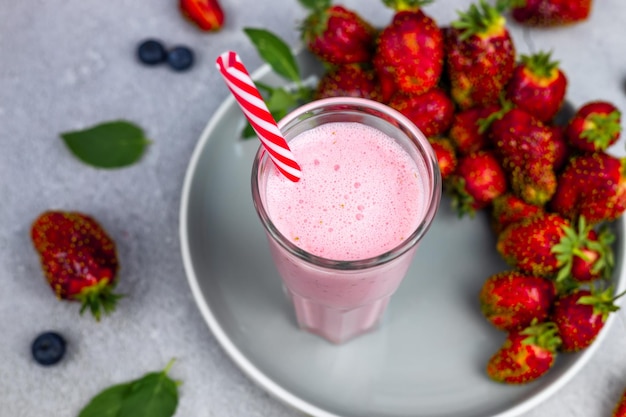 Strawberry smoothie or milkshake with berries and mint in a glass on a gray background Summer cocktail milkshake and refreshing organic concept Healthy eating vegetarian food concept