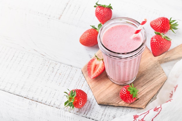 Strawberry smoothie Vegan smoothie or milkshake from strawberry banana and mint on white wooden table background Clean eating alkaline diet Top view Mock up