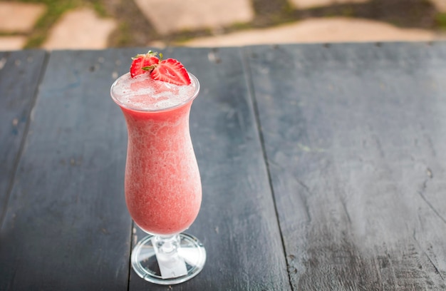 Strawberry smoothie on wooden table Strawberry milkshake on wooden table with blurred background Close up of healthy strawberry smoothie on wood with blurred background