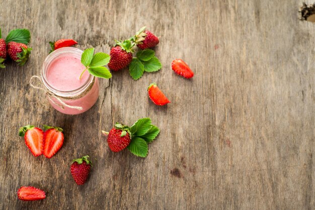 Strawberry smoothies in glass on wooden background. Top view. Copy space