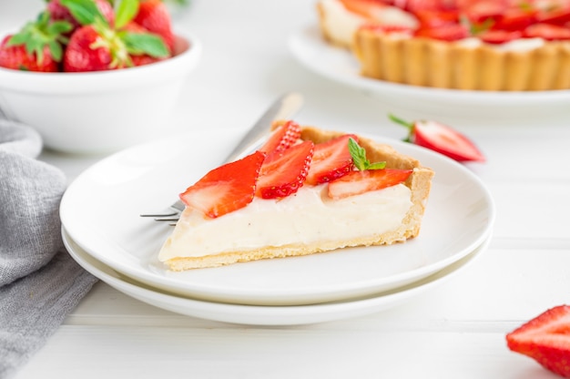 Photo strawberry tart with custard cream on a plate on a white wooden background. copy space.