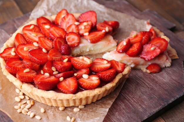 Strawberry tart on wooden tray, on rustic wooden background