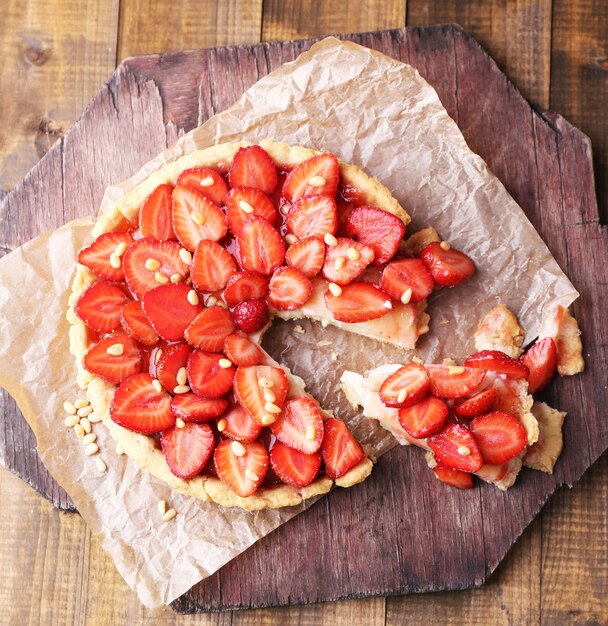 Strawberry tart on wooden tray, on rustic wooden background