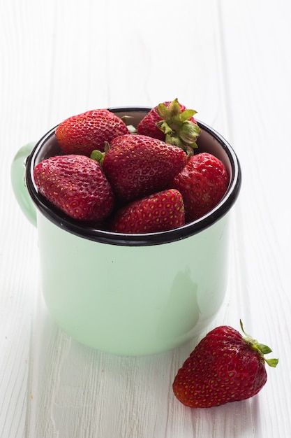 Strawberry in tea cup on a white wooden table