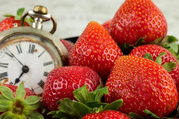 Tempo di fragole. fragole e vecchio orologio.