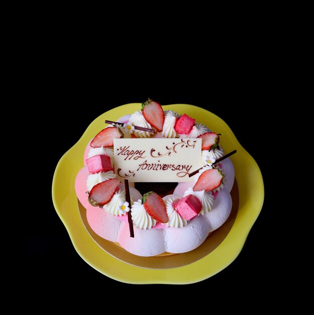 Strawberry vanilla mousse cake with edible white chocolate greeting card isolated on black background