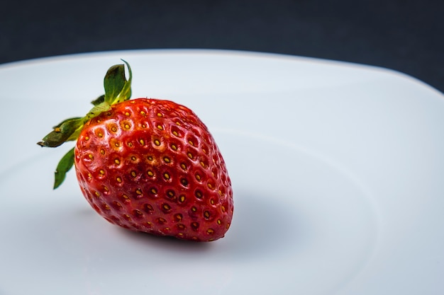 A strawberry on a white plate. Nice and healthy food