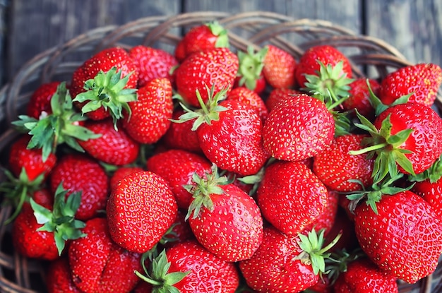 Strawberry in wicker plate on wooden background