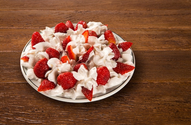 Strawberry with chantilly cream in a dish on a wooden table