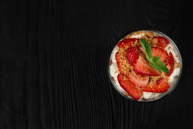 Strawberry with cookie and cream dessert decorated with mint leaf on black wooden background with co...