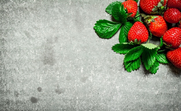 Strawberry with green leaveson stone table.