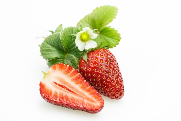 Strawberry with leaves and flower with one cut in half on white background