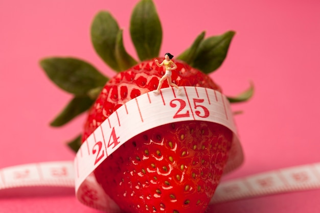 Strawberry with measure tape on pink background