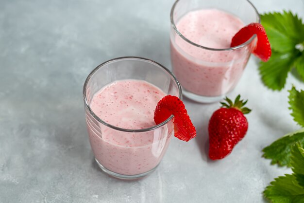 Frullati di fragole e yogurt su un tavolo grigio. decorato con fiori di sambuco e fragole. alimentazione sana, dieta.