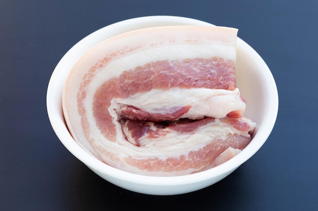 Streaky pork in white bowl on dark background