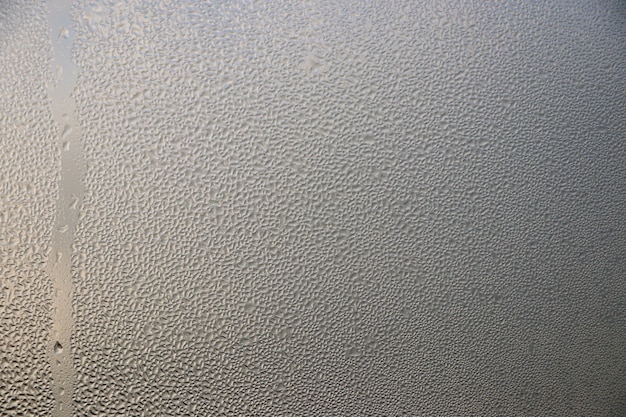 Stream drops on window glass with sunlight abstract on glass background