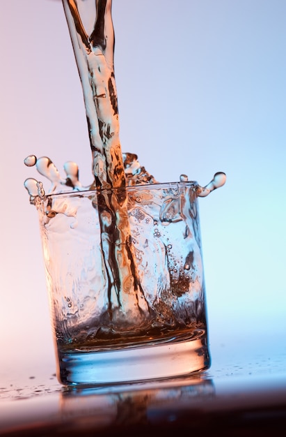 Foto il ruscello che riempie di alcol un bicchiere vuoto