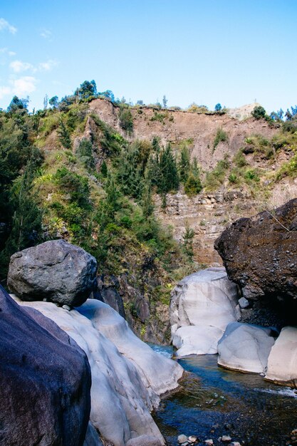 Stream flowing through rocks in river against sky