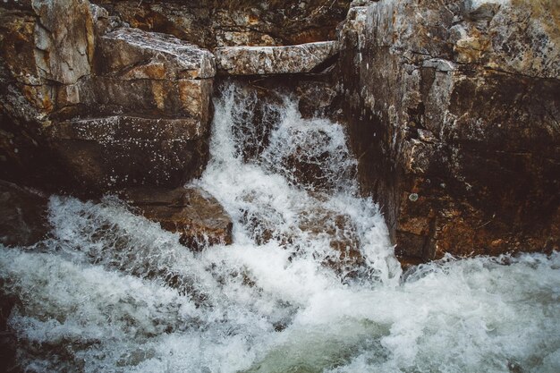 石のベッドで流れる岩の間の速い山川水は流れの渦で沸騰します