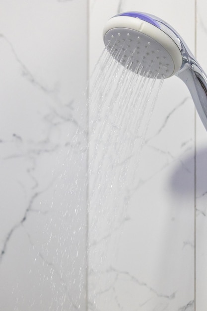 Foto flusso d'acqua che spruzza fuori dalla doccia nel bagno moderno, getti d'acqua pulita che scorrono dalla doccia