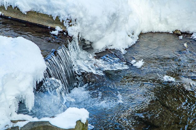 丸い雪の凍った水で流れる冬の季節の低温