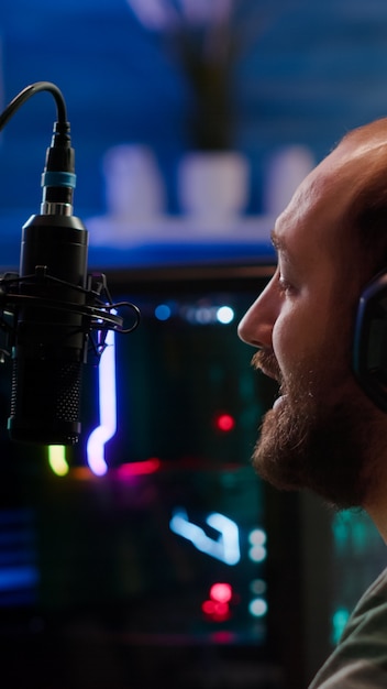 Streamer man talking into microphone with other players during space shooter tournament. Online streaming cyber performing video games competition using professional headphones and stream chat