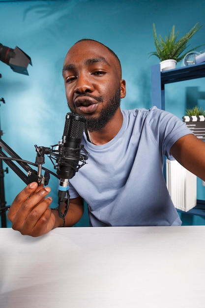 Streamer recording video for internet vlog and speaking with subscribers while holding camera. Young african american blogger talking in mic while streaming online portrait