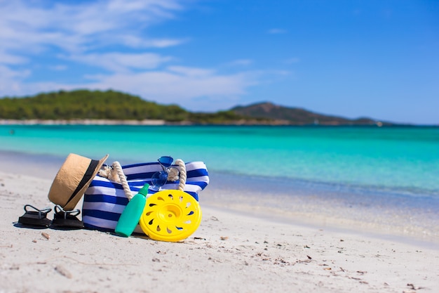 Streepzak, strohoed, zonnebrandcrème en handdoek op strand