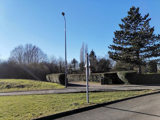 Street amidst field against clear blue sky