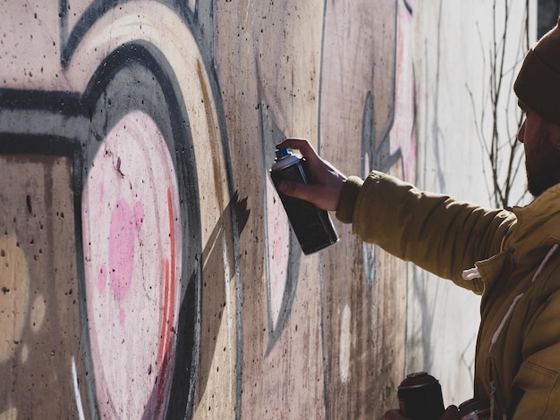 street artist draws colorful and vibrant graffiti modern art concept with city guy artist applies bright graffiti on gray wall