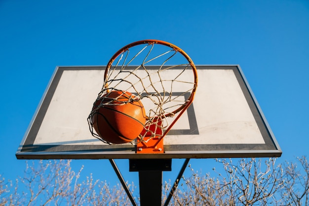 Фото Уличный баскетбольный мяч, падающий в обруч, городская молодежная игра.