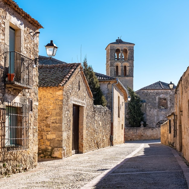 Street of beautiful medieval buildings with church tower in the background in the monumental city of Pedraza Segovia Spain