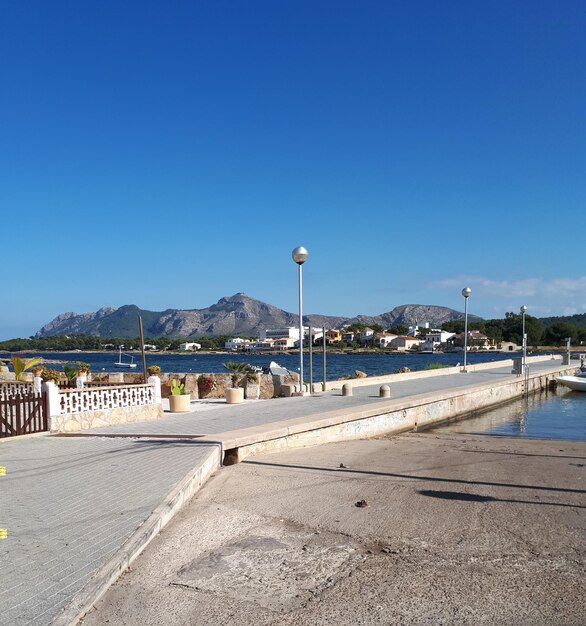 Photo street by footpath against blue sky and habor in alcudia spain