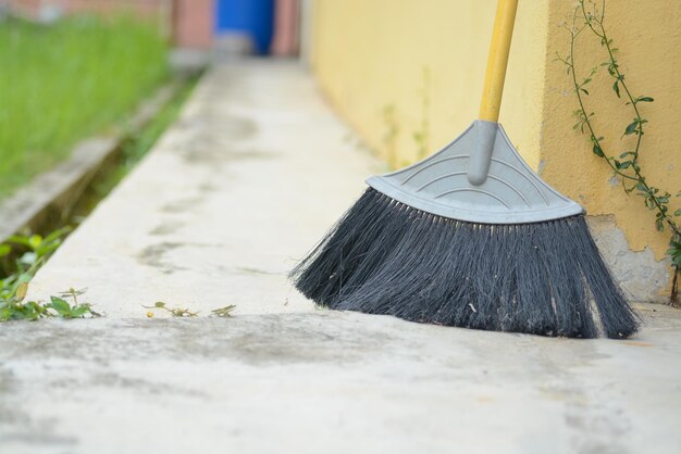 A street cleaning broom is leaning against a concrete wall