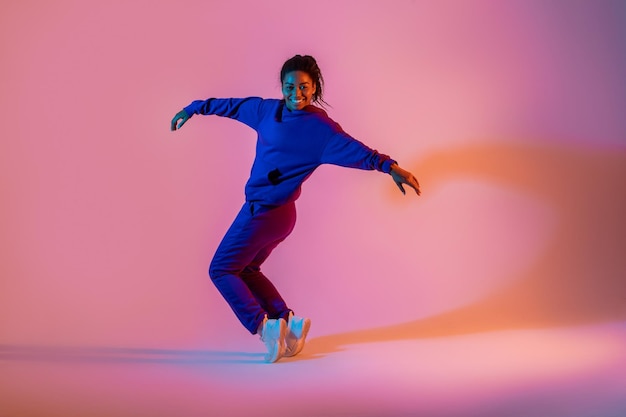 写真 ストリート ダンス スタイル ネオン ピンク ライト スタジオ背景空き領域で踊る幸せな黒人女性ヒップホップ ダンサー